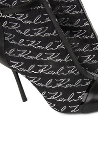 Mustad musta kõrge kontsaga king, mis on kaetud sametmaterjaliga, kaunistatud hõbedaste rhinestone'idega, mis on paigutatud ülemise osa peal kuldvõtmekirja mustris.