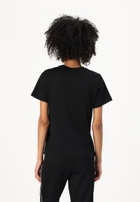 Black cotton t-shirt with short sleeves, a crew neckline, and a straight cut. Simple design, soft texture, and minimal detailing on the back.