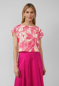 Bloem motief top met roze en crèmekleurige tinten, met korte mouwen en een geplooide halslijn, gecombineerd met een roze rok.
