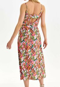 Kukkakuvioinen midi-mekko, jossa on säädettävät olkaimet. Mekossa on leikattu selkäosa, ja sen valkoisella taustalla on kirkkaan pinkkejä, vihreitä ja oransseja lehtikuvioita.