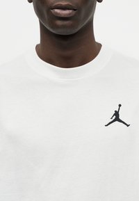 Λευκό φούτερ με μαύρο κεντημένο λογότυπο Jumpman στο αριστερό στήθος, στρογγυλή λαιμόκοψη και μαλακό βαμβακερό υλικό με απαλό υφή.