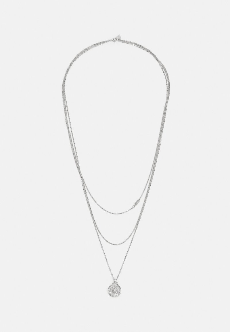 Collier en chaîne d'argent superposée avec trois brins et un pendentif rond finement décoré sur la chaîne la plus longue.