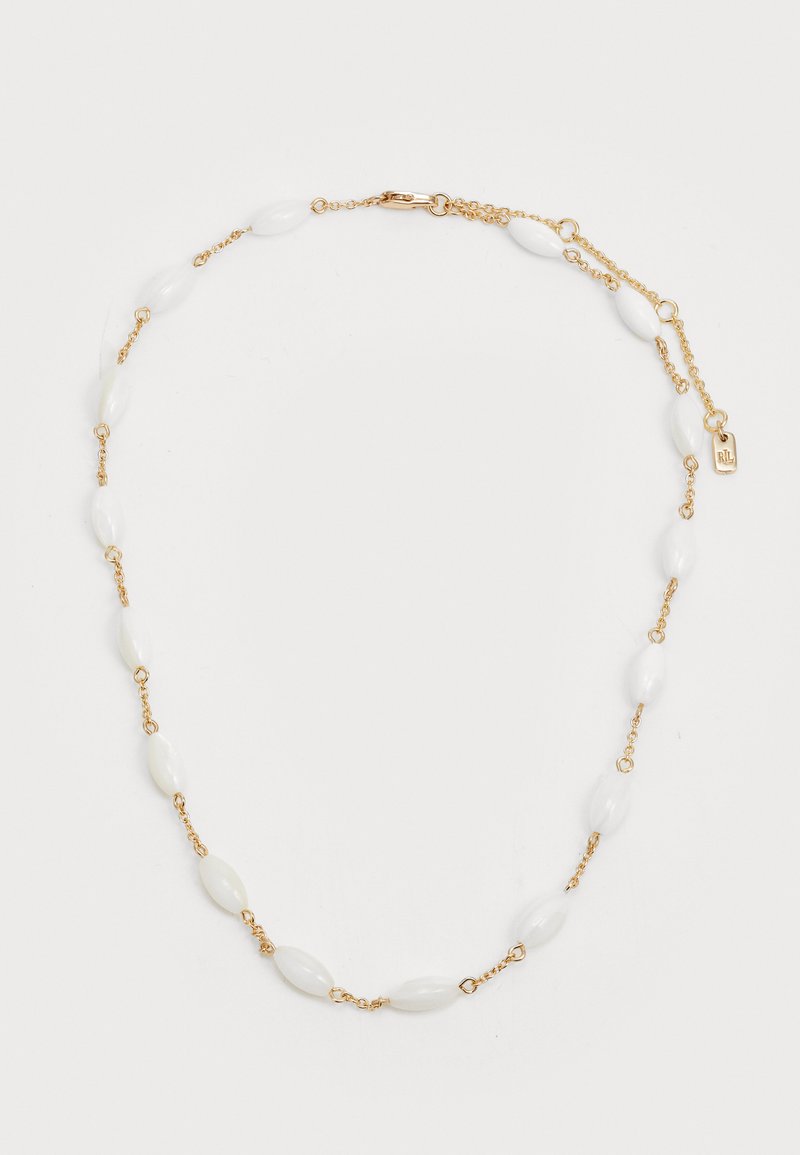 Zlatý náhrdelník reťaz s bielymi oválnymi korálkami rozptýlenými medzi malými spojkami. Uzáver s označením. Hladký povrch.