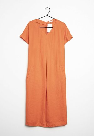 Pomarańczowa sukienka z krótkim rękawem, sięgająca do kolan, z dekoltem w serek i kieszeniami po bokach, wisząca na czarnym wieszaku z białą metką z ceną.