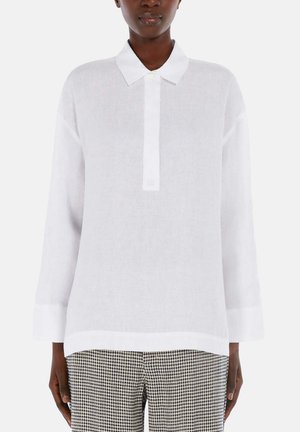Witte, langwerpige linnen blouse met een kraag en knopenlijst. Gecombineerd met zwart-witte geblokte broek.