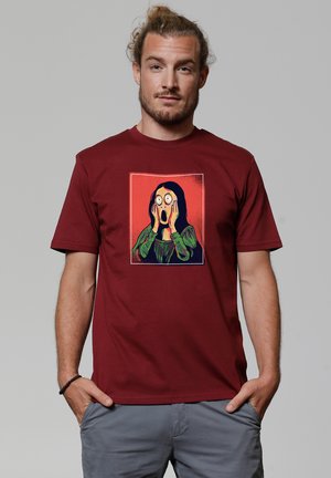 Bordeaux katoenen t-shirt met een grafische print van een schreeuwende figuur in levendig geel en groen op een rode achtergrond. Korte mouwen.