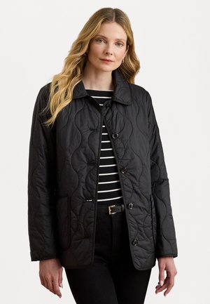 Veste matelassée noire avec un col, un devant à boutons et des poches latérales, portée sur un haut à rayures noir et blanc. Texture lisse.