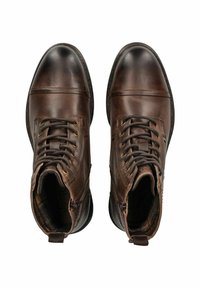 Botas de tobillo de cuero marrón con punta redondeada, diseño de cordones y ojales de metal. Acabado texturizado con suela de goma negra en contraste.