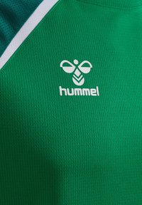 Tessuto sportivo verde con logo hummel bianco, che presenta un'ape stilizzata sopra il nome del marchio, accanto a una striscia diagonale bianca e verde scuro.