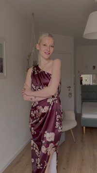 Gili bordo spalvos satino suknelė su gėlių raštu, asimetrišku iškirpte ir suglamžytu dizainu. Šonuose turi plyšį, suteikiantį papildomo žavesio.