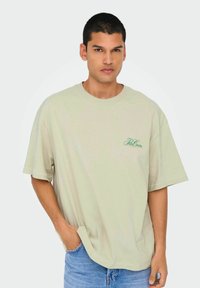 Helles grünes Baumwoll-T-Shirt mit kurzen Ärmeln und lockerer Passform. Verfügt über ein kleines grünes Logo auf der Brust und einen Rundhalsausschnitt.