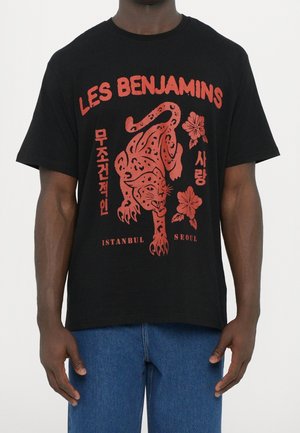 Sort t-shirt med rød grafik af en brølende leopard, blomster og teksten "LES BENJAMINS," "ISTANBUL," "SEOUL" og koreanske tegn.