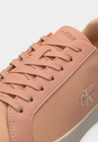 Αθλητικό παπούτσι Calvin Klein σε απαλό ροδακινί χρώμα με κορδόνια στο ίδιο χρώμα, ανάγλυφο λογότυπο CK στη πλευρά και υφασμένη ελαστική σόλα.