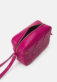 Růžová kožená taška s prošíváním a zlatým zipem, obdélníkový tvar, nosný popruh, vystouplé logo "Valentino" na jedné straně a ploché dno.
