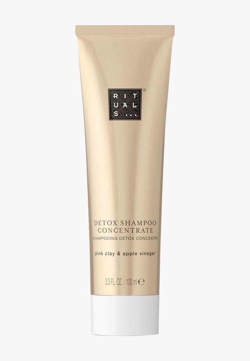 Tube doré de concentré de shampooing détox avec un capuchon blanc, étiqueté « argile rose & vinaigre de pomme ». Logo noir près du haut, design minimaliste.