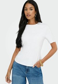 Vit kortärmad T-shirt med rund hals, tillsammans med blå denimjeans. Tyget verkar slätt och lätt.