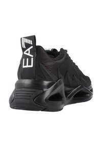 Scarpe da ginnastica nere con tomaia in tessuto texture, design angolare, suola in gomma spessa e accenti prominenti sul tallone. Marchio sulla linguetta del tallone.