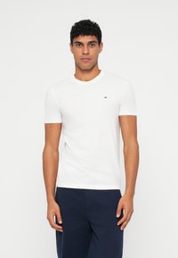 Λευκό T-shirt από βαμβάκι, με στρογγυλή λαιμόκοψη, κοντά μανίκια και ένα μικρό, έγχρωμο λογότυπο στο στήθος.