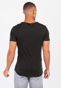 Zwarte T-shirt met korte mouwen en een ronde hals, gemaakt van zacht materiaal, met een gebogen zoom en subtiele textuur.