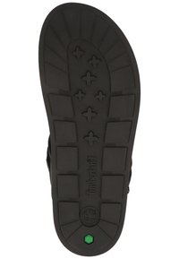 Semelle extérieure en caoutchouc noir avec un motif texturé, présentant un logo central et un accent vert près du talon. Conçu pour l'adhérence et la durabilité.