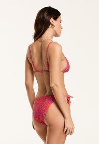 Mitmevärvilisest paisley-mustriga bikiinimäärast, millel on kolmnurkne topp õhukeste rihmadega ja küljetõmmatav alaosa, valmistatud venivast kangast.