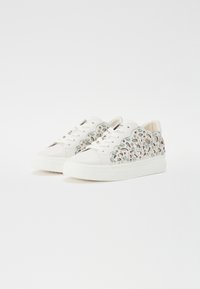 Hvite sneakers med et dekorativt utskjæring design med turkise og sølvfargede detaljer, teksturerte materialer og en tykk gummisåle.