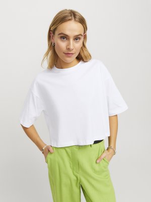 Tricou alb din bumbac tăiat, cu guler rotund și mâneci scurte, asociat cu pantaloni din in verzi, texturați, având o croială lejeră.