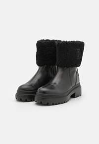 Czarne skórzane botki za kostkę z sztucznym futrem, masywną gumową podeszwą i zamkiem błyskawicznym z boku. Posiadają wytłoczone logo na futrze, elegancki design.