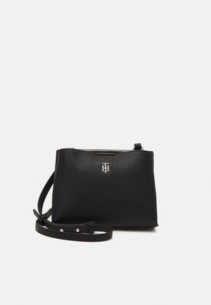 Zwarte gestructureerde leren crossbodytas met zilveren ritssluiting en verstelbare band, met een klein zilveren logo aan de voorkant.