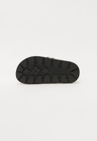 Black rubber outsole with a pronounced tread pattern featuring triangular and diamond shapes. Engraved brand name "Steve Madden."