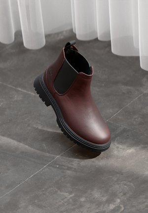 Burgundy leather ankle boot with a black elastic side, rugged black sole, and a pull tab at the back for easy wear.