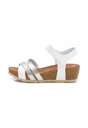 Sandalias blancas con suela de cuña de corcho, que cuentan con tiras cruzadas metálicas en color plata y una correa de tobillo ajustable para un ajuste seguro. La textura combina patrones lisos y de reptil.