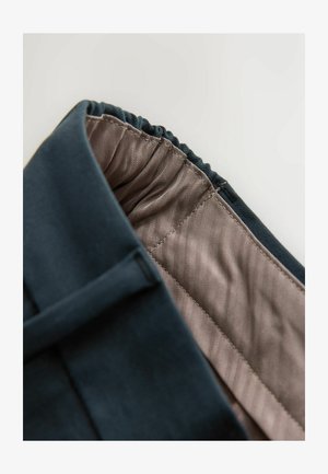 Temno modra oblačila z nabranim pasom, ki razkriva svetlo rjavo notranjost z ribjo kostjo in gladko teksturo.