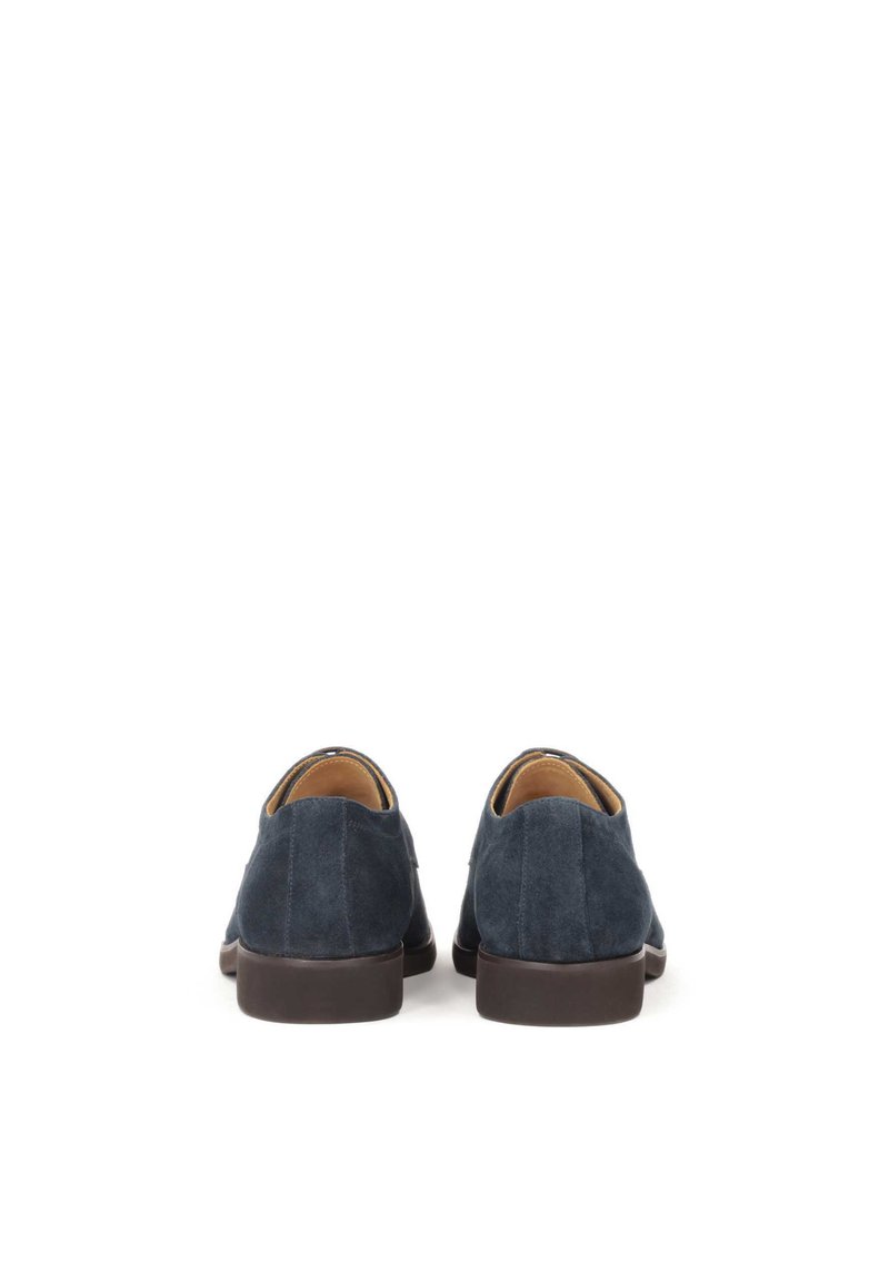 Chaussures en suède bleu marine foncé avec une texture lisse, bout arrondi et une semelle en caoutchouc marron foncé, basse. Pas de matériel ou d'accents visibles.