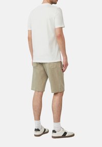 Witte katoenen t-shirt, korte mouwen, gecombineerd met lichtgroene denim shorts en witte sneakers met zwarte accenten. Zichtbare stiksels van de achterzak.