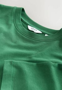 Green cotton t-shirt with a relaxed fit, featuring a rounded neckline and a smooth texture. Label reads "NEXT".
