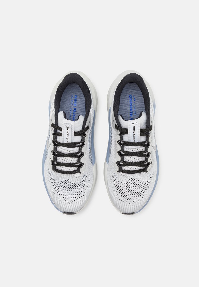 Un paio di scarpe da corsa Nike bianche e azzurro chiaro con lacci neri, viste dall'alto su uno sfondo bianco semplice.