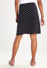 Czarna spódnica w kropki z białymi plamkami, wykonana z lekkiego materiału. Posiada falbaniasty dół i luźny krój.