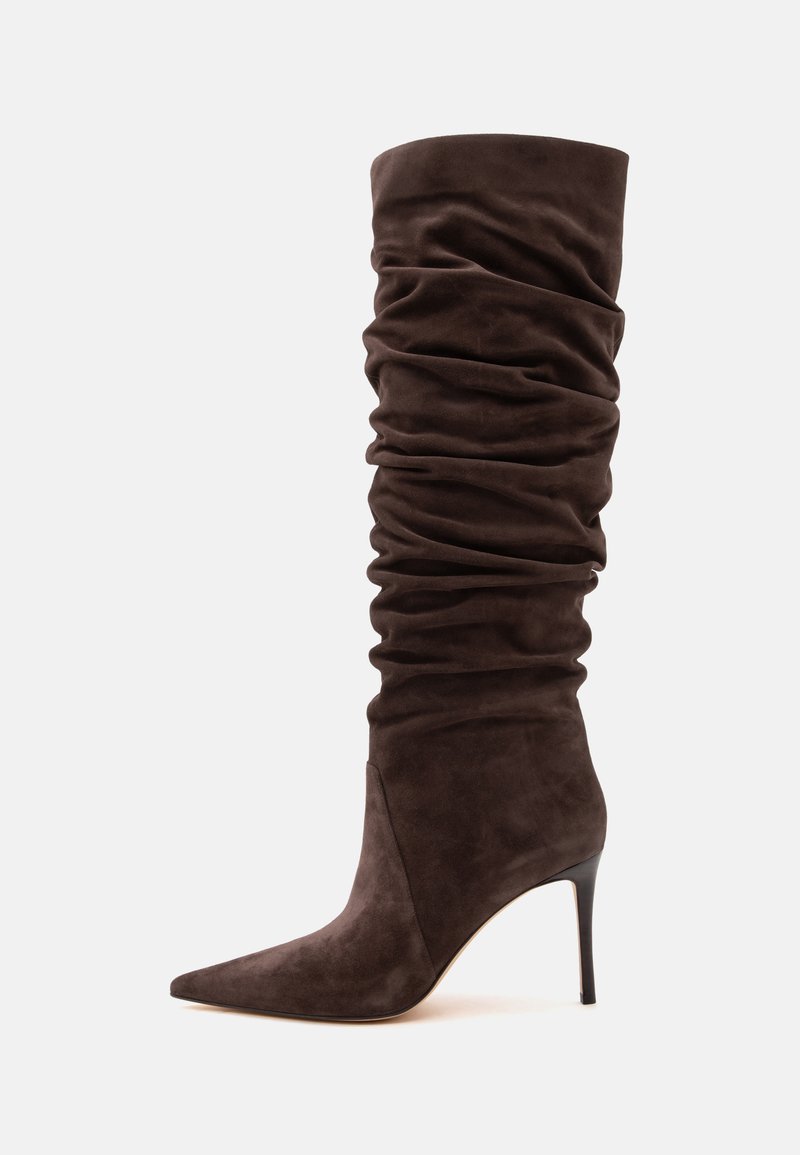 Botte marron en daim montant jusqu'au genou avec tige ample et bout pointu sur un talon aiguilles haut sur fond uni.