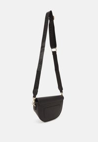 Borsa a tracolla nera in pelle con forma curva, chiusura a patta magnetica e tracolla regolabile testurizzata con il logo in finitura lucida.