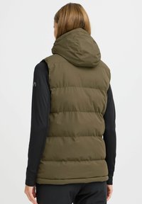 Gilet rembourré vert olive avec capuche, fabriqué en tissu lisse. Présente une silhouette ajustée et une texture douce. Convient pour le superposition ou les activités en extérieur.