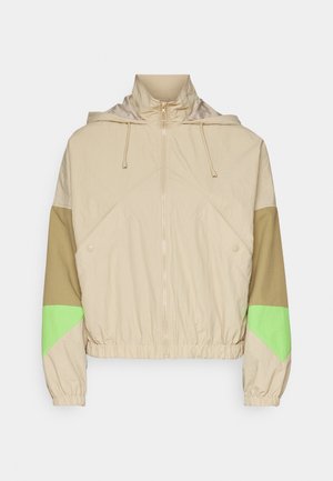 Veste beige avec capuche, présentant des blocs de couleur verts et bruns, une fermeture éclair au centre, des poignets élastiques et un ourlet resserré. Tissu texturé.