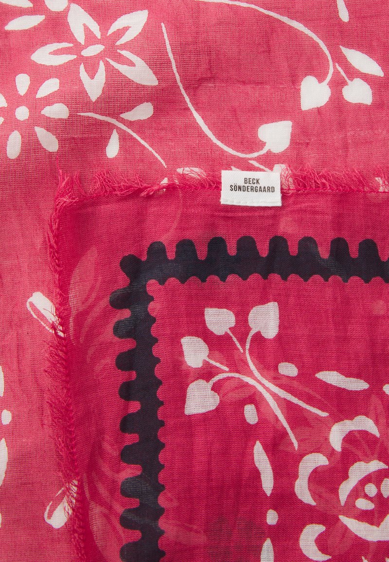 Czerwona chustka w kwiaty z białymi i czarnymi wzorami. Lekki, przezroczysty materiał z frędzlami. Metka nosi napis "Beck Søndergaard".