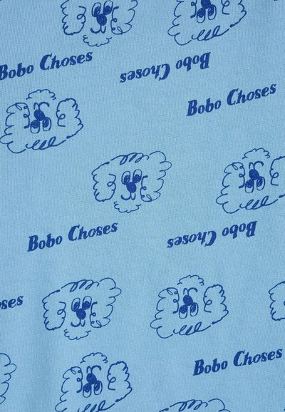 Tissu bleu à motifs répétés de visages de chien dessinés en bleu foncé et le texte "Bobo Choses" dans différentes orientations.