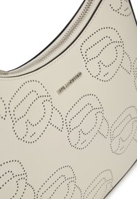 Borsa hobo in morbida pelle color crema con motivo logo perforato, hardware in argento e chiusura con zip lungo il bordo superiore. Finitura a superficie liscia.
