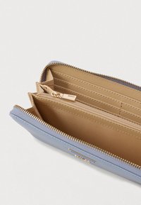 Zils teksturēts maks ar zelta rāvējslēdzēju un iekšējiem nodalījumiem. Tam ir krēmkrāsas oderējums un vairāki karšu nodalījumi.