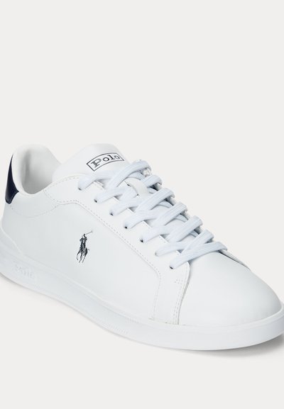 Hvid lav sko med hvide snørebånd, sort Polo-logo på siden og sort detalje på hælen mod en ensfarvet hvid baggrund.