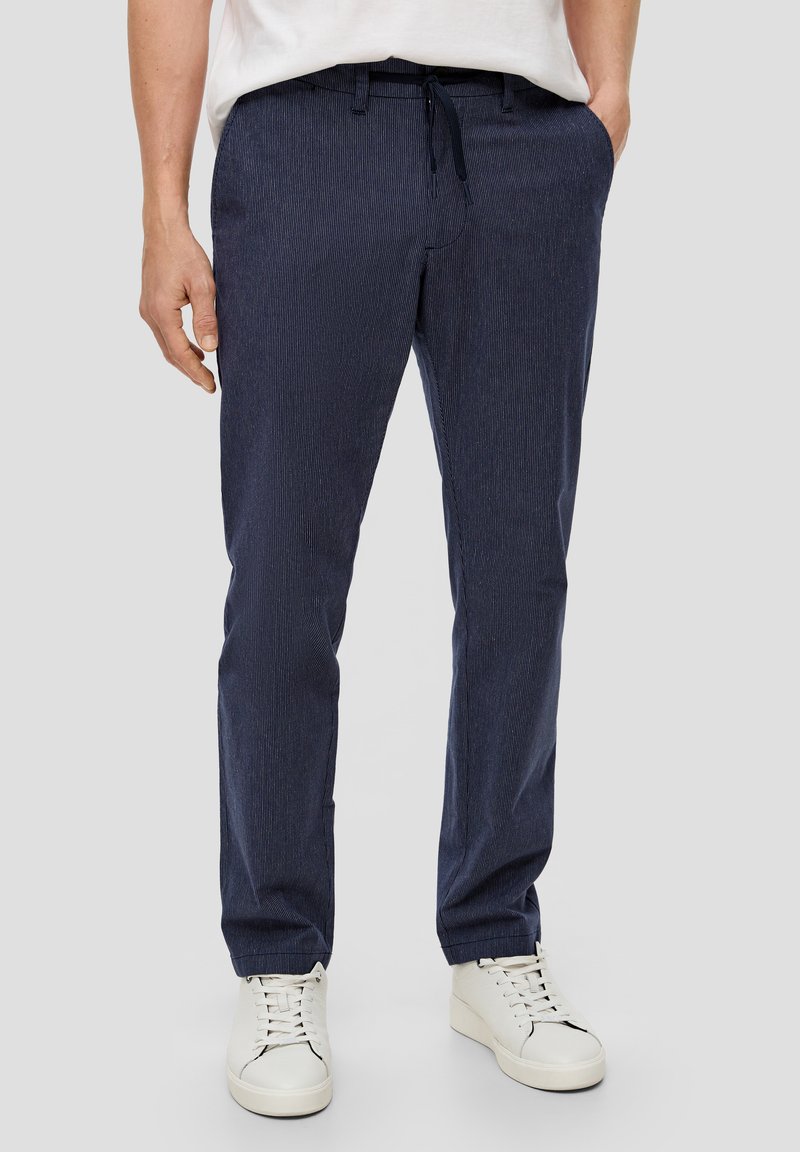Navy-blaue gestreifte Hose mit einem Kordelzugbund, schlanke Passform und glatter Textur, kombiniert mit weißen Sneakers.