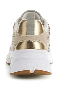 Baskets blanches et dorées pour femmes vues de l'arrière, avec une semelle blanche épaisse et une languette grise, portant la marque "GUESS" sur le talon.