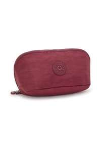 Bolsa de tela roja con forma redondeada, cierre con cremallera y un parche de logo circular. Textura suave y diseño discreto.